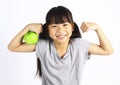 A little girl flexes her muscle while showing off the apple