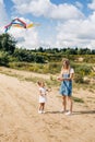 A little girl flies a kite with her older sister and runs away from her