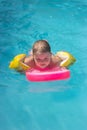 Little girl on the floating board, learns to swim in the pool