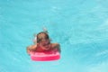 Little girl on the floating board, learns to swim in the pool