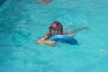 Little girl on the floating board, learns to swim in the pool