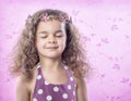 Little girl in flower crown with eyes closed on pink background Royalty Free Stock Photo