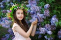 Little girl with a flower wreath on her head standing in the park on a sunny morning and smiling. Look at camera Royalty Free Stock Photo