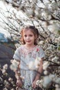 A little girl in a flowering garden in the spring. Stylish decocha amid white plum flowers