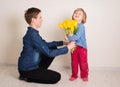 Little girl with flowers kissing her elder brother. Teen boy congratulates his little sister and gives her flowers tulips Royalty Free Stock Photo