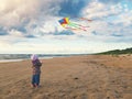 Little girl flying a kite on the beach at sunset Royalty Free Stock Photo
