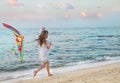 Little girl with flying kite on beach at sunset Royalty Free Stock Photo