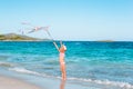 Little running girl with flying kite on tropical beach. Kid play on ocean shore. Royalty Free Stock Photo