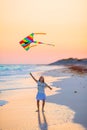 Little girl with flying kite on tropical beach at sunset. Kid play on ocean shore. Child with beach toys. Royalty Free Stock Photo