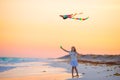 Little girl with flying kite on tropical beach at sunset. Kid play on ocean shore. Child with beach toys. Royalty Free Stock Photo