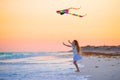 Little girl with flying kite on tropical beach at sunset. Kid play on ocean shore. Child with beach toys. Royalty Free Stock Photo