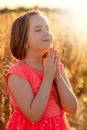 Little girl folded her hand and close your eyes in praying, dreaming in field outdoors. Child praying. Royalty Free Stock Photo