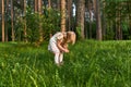 Little girl in a forest glade looks at flowers Royalty Free Stock Photo