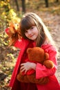 Little girl in forest with maple leaves and bear