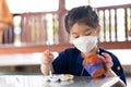 Little girl is fun paints clay objects. Workshop in lesson in class farm nature. Happy child wearing medical white mask Royalty Free Stock Photo