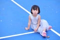 The little girl is funny face while sitting on the tennis court.