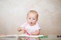 Little girl with a funny facial expression enthusiastically draws with colored pencils in an album Royalty Free Stock Photo