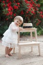 Little girl in rose garden next to a big bush of red roses Royalty Free Stock Photo