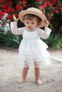 Little girl in rose garden next to a big bush of red roses Royalty Free Stock Photo