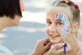 Little girl getting her face painted by face painting artist.