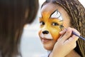 Little girl getting her face painted by face painting artist. Royalty Free Stock Photo