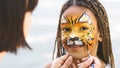 Little girl getting her face painted by face painting artist. Royalty Free Stock Photo