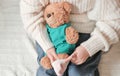 little girl gettng her teddy bear ready for a street walk. putting on clothes on a toy bear. crop view. Royalty Free Stock Photo