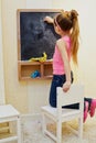 Little girl girl writes with chalk on blackboard Royalty Free Stock Photo