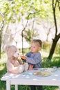 Little girl gives tea from a cup to a teddy bear at a table in the garden at a tea party Royalty Free Stock Photo