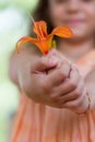 Little girl gives you orange lilly flower Royalty Free Stock Photo