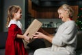 Little girl giving a big wrapped present box to her grandma for christmas Royalty Free Stock Photo