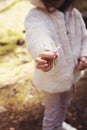 A little girl giving flower crocus. A kid in the mountain. Pine forest with wildflowers Royalty Free Stock Photo