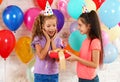 Little girl giving her friend birthday gift at party