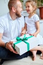 Little girl is giving her handsome father a gift box on Father`s day Royalty Free Stock Photo