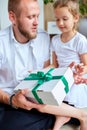 Little girl is giving her handsome father a gift box on Father& x27;s day Royalty Free Stock Photo