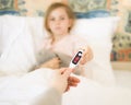 Little girl giving her mother digital thermometer after measuring temperature. child ill and has high temperature Royalty Free Stock Photo