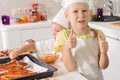 Little girl giving a thumbs up as she bakes pizza