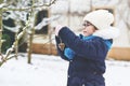 Little girl with glasses feeds birds on winter. Happy smiling preschool child hanging selfmade bird seed heart on tree Royalty Free Stock Photo