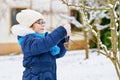 Little girl with glasses feeds birds on winter. Happy smiling preschool child hanging selfmade bird seed heart on tree Royalty Free Stock Photo