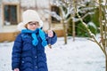 Little girl with glasses feeds birds on winter. Happy smiling preschool child hanging selfmade bird seed heart on tree Royalty Free Stock Photo