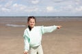 Little girl in glasses points her finger at her wind kite standing on a sandy beach