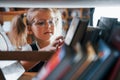 Little girl in glasses searching for a book in the library. Conception of education