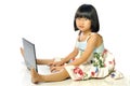 Little girl in glasses sitting on floor using a laptop, white ba Royalty Free Stock Photo