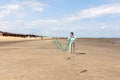 A little girl in glasses stands on an empty beach flying a kite Royalty Free Stock Photo