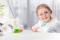 Little girl in goggles with flasks in laboratory looking at camera