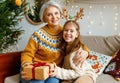 Little girl granddaughter giving Christmas gift box to smiling grandmother during winter holidays Royalty Free Stock Photo