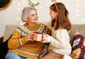 Little girl granddaughter giving Christmas gift box to smiling grandmother during winter holidays Royalty Free Stock Photo
