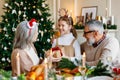 Little girl granddaughter giving Christmas gift to surprise grandmother during Xmas family dinner Royalty Free Stock Photo