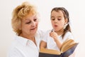 Little girl with grandma reading interestng book