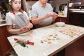 Little girl with grandmother in the kitchen sculpts dumplings